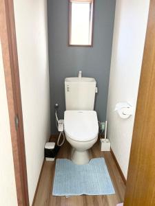 a small bathroom with a toilet with a blue rug at ラフォーレハウス in Hitoyoshi