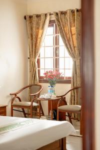 a room with a table and chairs and a window at Hùng Phong Hotel - Near Dalat Market in Da Lat