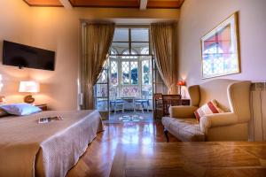 a bedroom with a bed and a chair and a window at Villa Mediteran Old Town, 5 En-Suites and Hot Tub in Dubrovnik