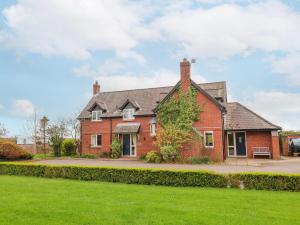 a large red brick house with a green lawn at Manor Wood in Coddington
