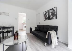 a living room with a black couch and a table at Celtic City Stay in Glasgow +3 photos