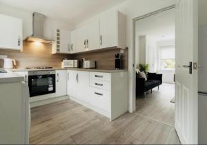a kitchen with white cabinets and a living room at Celtic City Stay in Glasgow