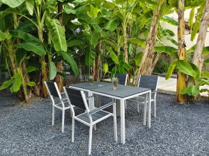 a table with four chairs and a table and trees at Chino Town at Yaowarat Phuket - SHA Plus in Phuket