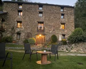 a stone house with a table and chairs in front of it at Mas La Casanova in Queralbs