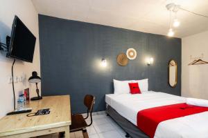 a bedroom with a bed and a desk with a television at RedDoorz near Exit Toll Tanah Baru Bogor in Bogor