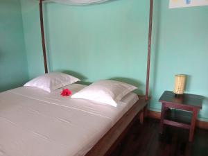 a bed with white sheets and a red flower on it at VILLA Paradisakely in Nosy Be