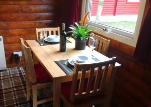 a wooden table with a bottle of wine and a plant at Pucks Glen Lodges - Log Cabins in a wonderful natural environment in Dunoon