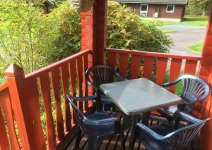 a table and four chairs on a porch at Pucks Glen Lodges - Log Cabins in a wonderful natural environment in Dunoon