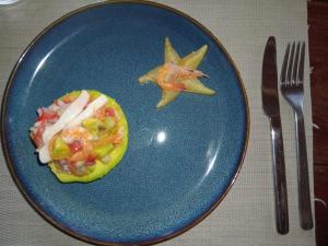 a blue plate with a pineapple cut in half next to a fork at VILLA Paradisakely in Nosy Be