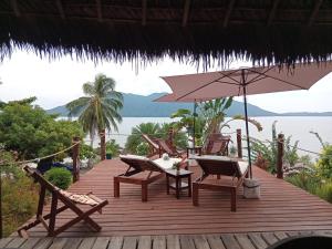a wooden deck with chairs and a table and an umbrella at VILLA Paradisakely in Nosy Be