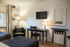 a hotel room with a desk and a tv on the wall at Sjögestad Motell in Vikingstad