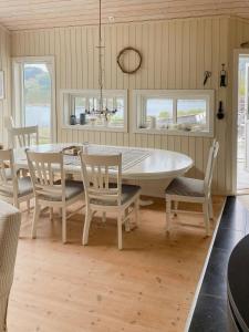 a dining room with a white table and chairs at Cozy Cabin With Økstrafjord View in Jelsa