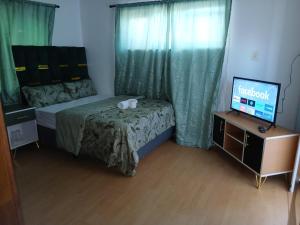 a small bedroom with a bed and a television at Tatami Guesthouse in Parow