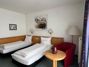 a hotel room with two beds and a red chair at Matchpoint Hotel in Altdorf bei Nuernberg