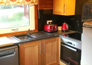 a kitchen with a sink and a microwave at Pucks Glen Lodges - Log Cabins in a wonderful natural environment in Dunoon