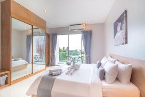a bedroom with a large white bed and a balcony at Lemonade Phuket Hotel -SHA Plus in Chalong
