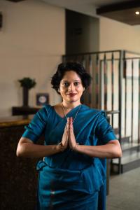 a woman in a blue dress standing in a room at Oak Ray City Hotel in Kandy