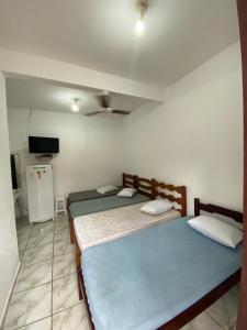 a bedroom with two beds and a television in it at Dina Suítes Flat's Caiçara in São Sebastião