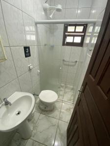 a white bathroom with a toilet and a sink at Dina Suítes Flat's Caiçara in São Sebastião +5 photos