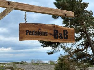 a wooden sign that reads regulations bbb hanging from a chain at Trädgårdscafé Pedalen B&B in Halmstad