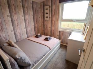 a small bedroom with a bed and a window at Moggs Retreat in Skegness