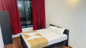 a bed in a room with red curtains and a window at EK Residency in Anaviratty +6 photos
