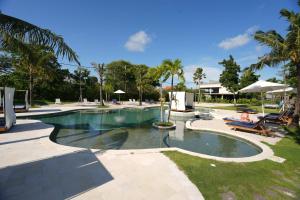 a swimming pool with benches and palm trees at Pronoia Beach Resort in Jimbaran