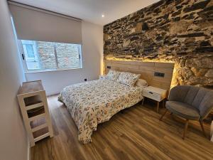 a bedroom with a bed and a stone wall at Apartamento Plaza de Armas 2 in Ferrol