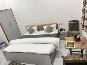 a bedroom with two beds with white sheets and a table at Ligree Hotel and Restaurant in Jatwāra