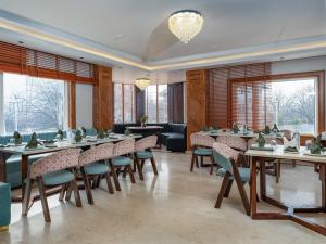 a dining room with tables and chairs and windows at Faiz Resort Pahalgam in Pahalgām