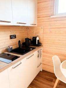 a kitchen with white cabinets and a sink and a table at Tiny House Cēsis in Cēsis
