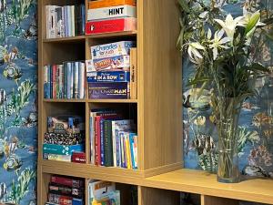 a book shelf filled with books and a vase of flowers at Seasides in Weymouth