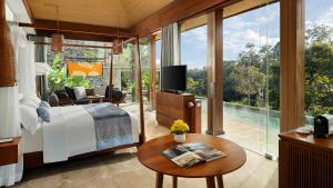 a bedroom with a bed and a tv and a pool at Maya Ubud Resort & Spa in Ubud