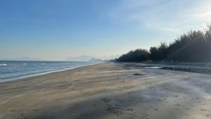 an empty beach with trees and water in the background at Luxe Sands Pran in Ban Nong Ban Kao