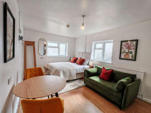 a bedroom with a bed and a table and a green couch at The Forest- Mosswood in Cambridge