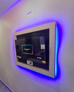 a tv mounted on a wall with purple lights at Tazinn in Wayanad