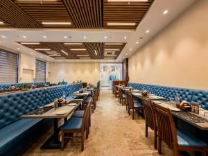 a restaurant with long tables and blue seats at ZiP By Spree Hotels Pandharpur in Pandharpur