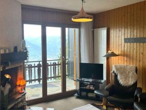 a living room with a television and a balcony at Apartment in Veysonnaz near Ski Gondola in Veysonnaz +131 photos
