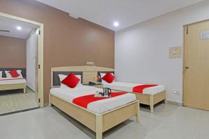 two beds with red pillows in a room at Hotel O Padmini Near Lakdikapool Metro Station in Hyderabad