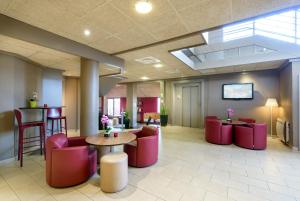 a lobby with red chairs and a table and a table andools at Campanile Toulouse Purpan in Toulouse