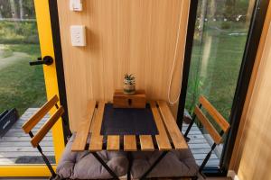 a wooden table sitting on a porch with a potted plant at Wilderness Whisper 1770 By Tiny Away in Agnes Water