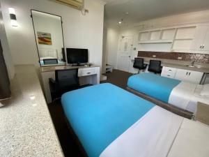 a room with two beds and a desk with chairs at Stonestown Suites in Balulang