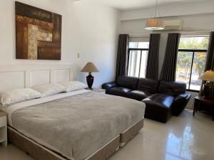 a bedroom with a large bed and a couch at Stonestown Suites in Balulang