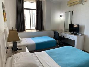 a hotel room with two beds and a desk and a mirror at Stonestown Suites in Balulang