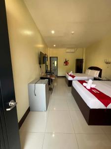 a hotel room with two beds and a desk at Hollywood Suites Gensan in General Santos