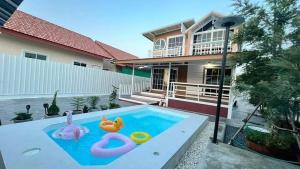 a house with a swimming pool with swans in it at Peace poolvilla sattahip พีซ พลูวิลล่า สัตหีบ in Ban Tao Than