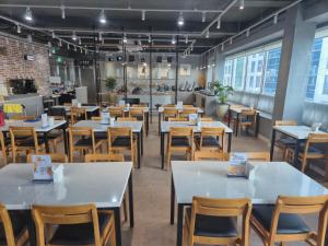 a dining room with white tables and wooden chairs at 광장관광호텔 in Pusan