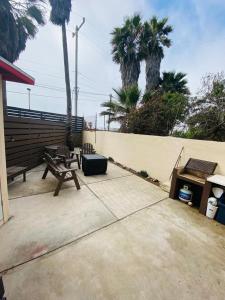 a patio with two benches and a fence and palm trees at Villas Serena Rosarito in Rosarito Beach