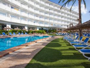 un hôtel avec des chaises longues et une piscine dans l'établissement Grupotel Maritimo, à Port d'Alcúdia