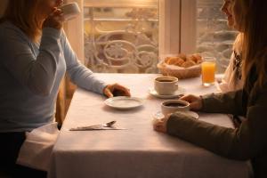 due donne sedute a un tavolo con tazze di caffè di Hôtel Foch a Lione